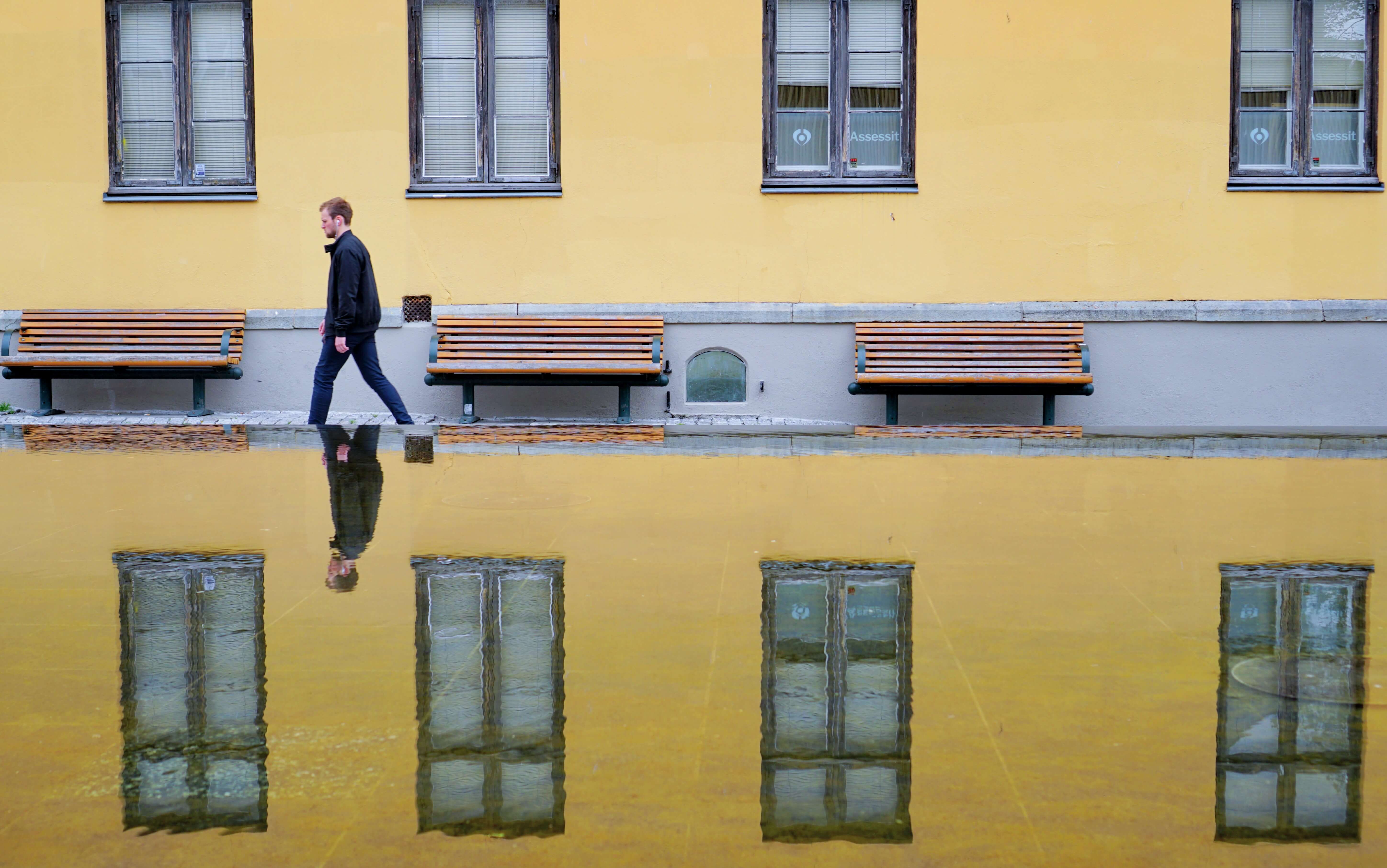 a man walking next to a yellow building